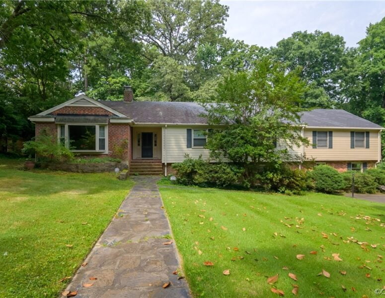 A split level home with green grass and a front walkway