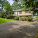A split level home with a driveway and greenery