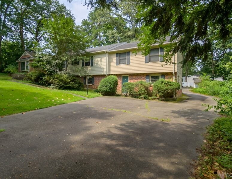 A split level home with a driveway and greenery