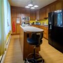 A picture of a kitchen with a black refrigerator and brown cabinets