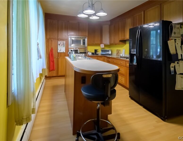 A picture of a kitchen with a black refrigerator and brown cabinets